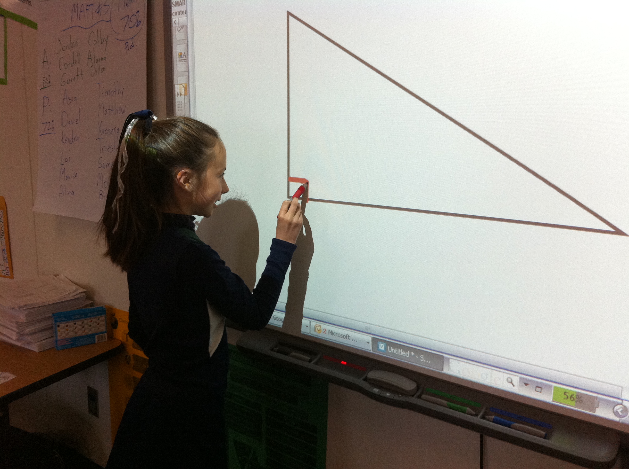 Reagan Elementary student Morgan Polley identifies a right angle with an interactive whiteboard. Going paperless and using more technology are cited by principal Robb Christopherson as ways to reduce costs and teach more effectively.