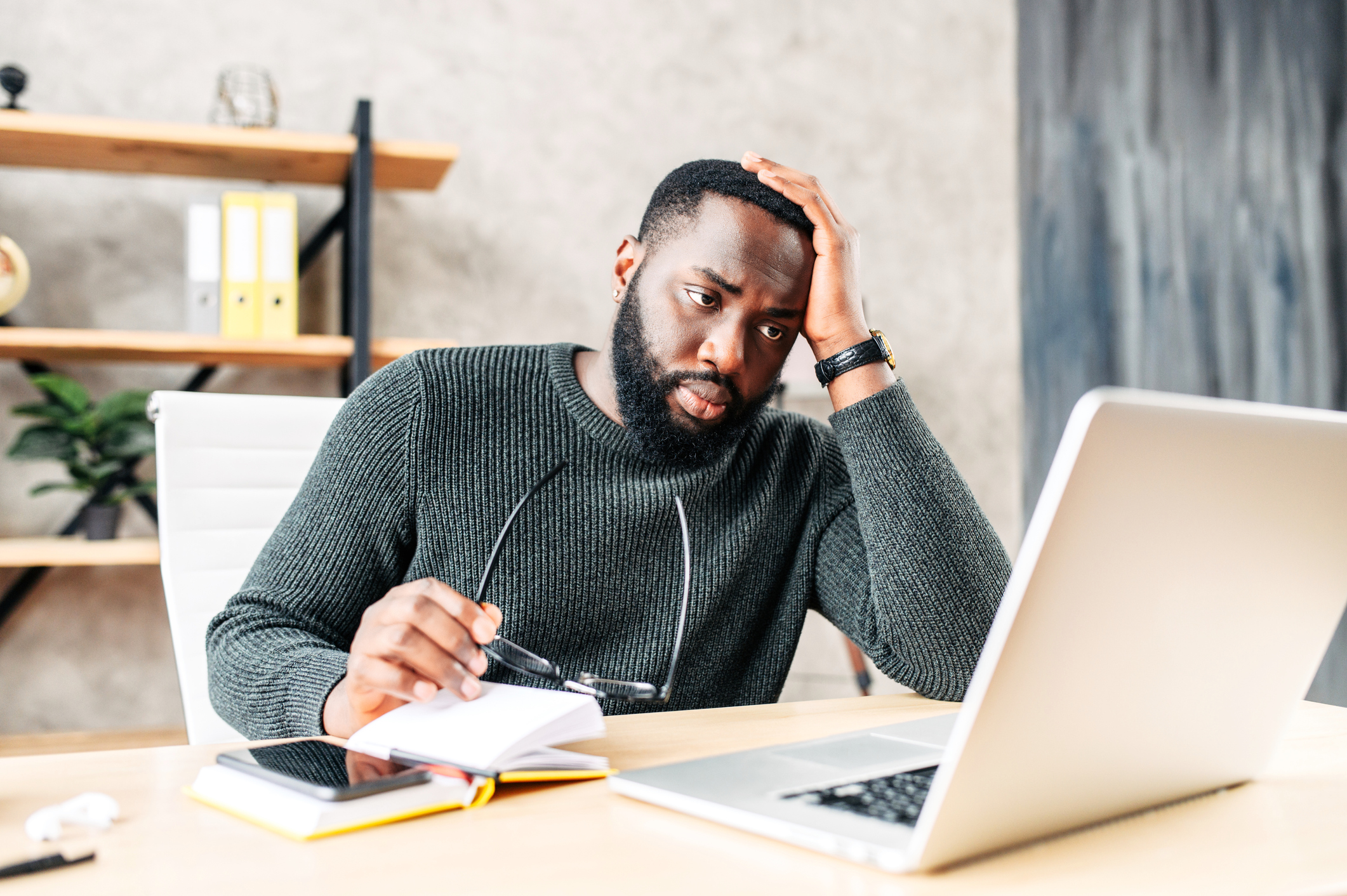 Frustrated sad black guy is watching at laptop screen